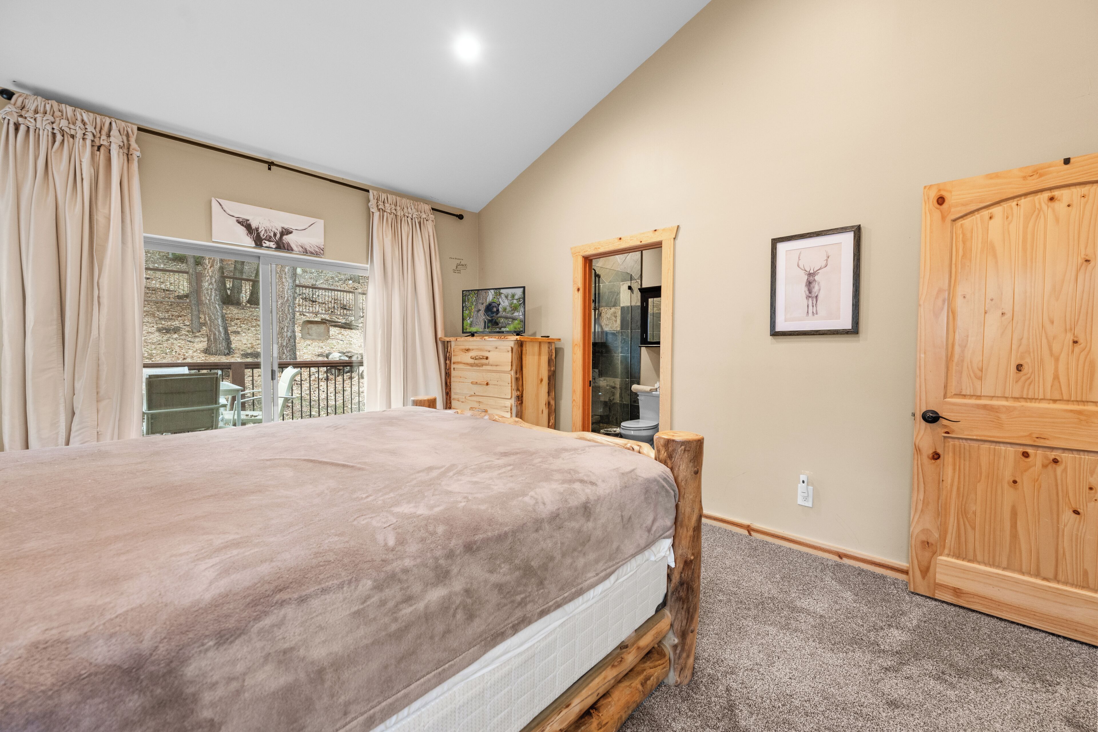 A bedroom with a bed, wooden wardrobe, a dresser, a mirror, and a window with curtains.