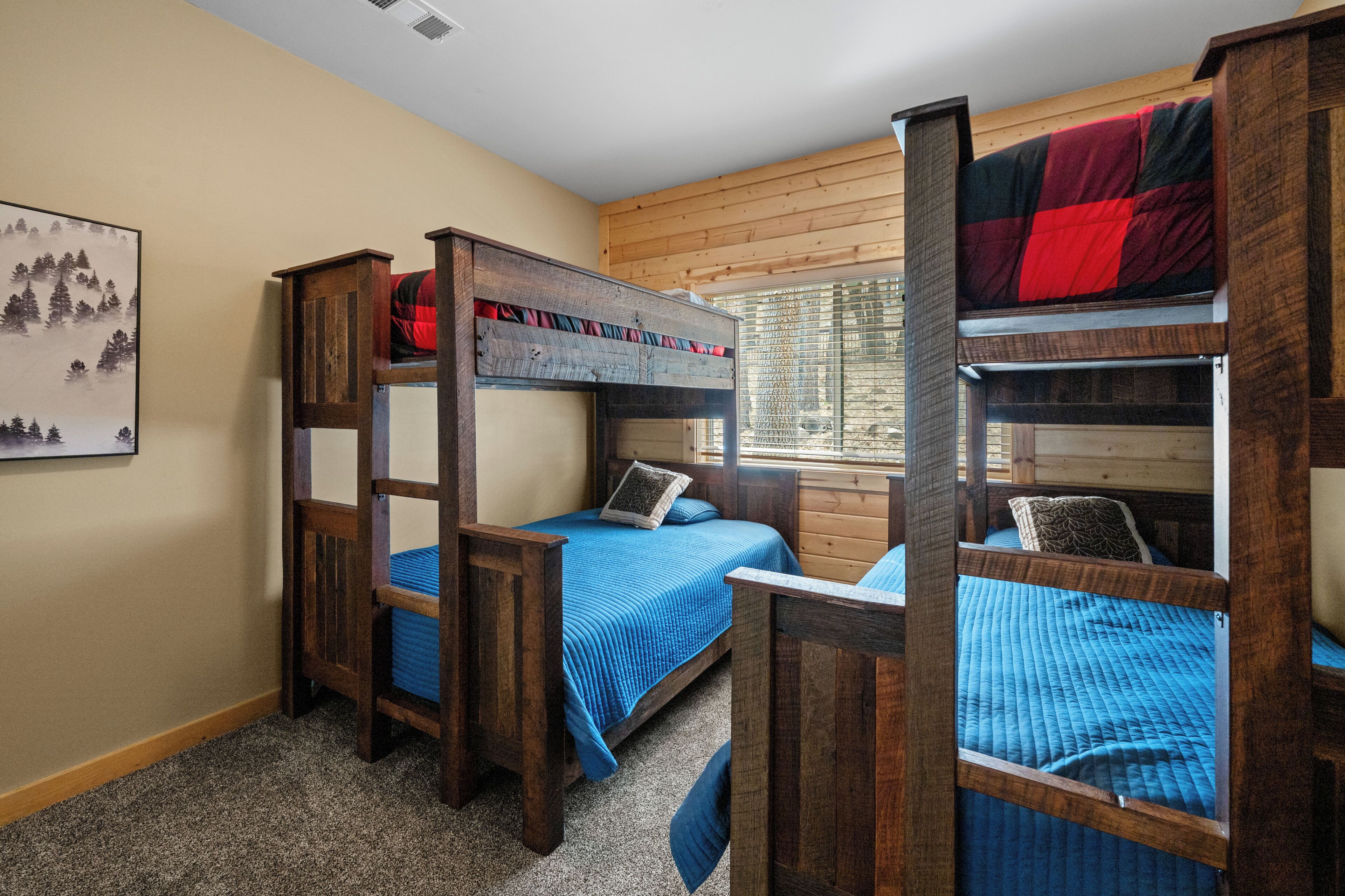 A dormitory room with bunk beds, wooden headboards, and a blue bedspread.