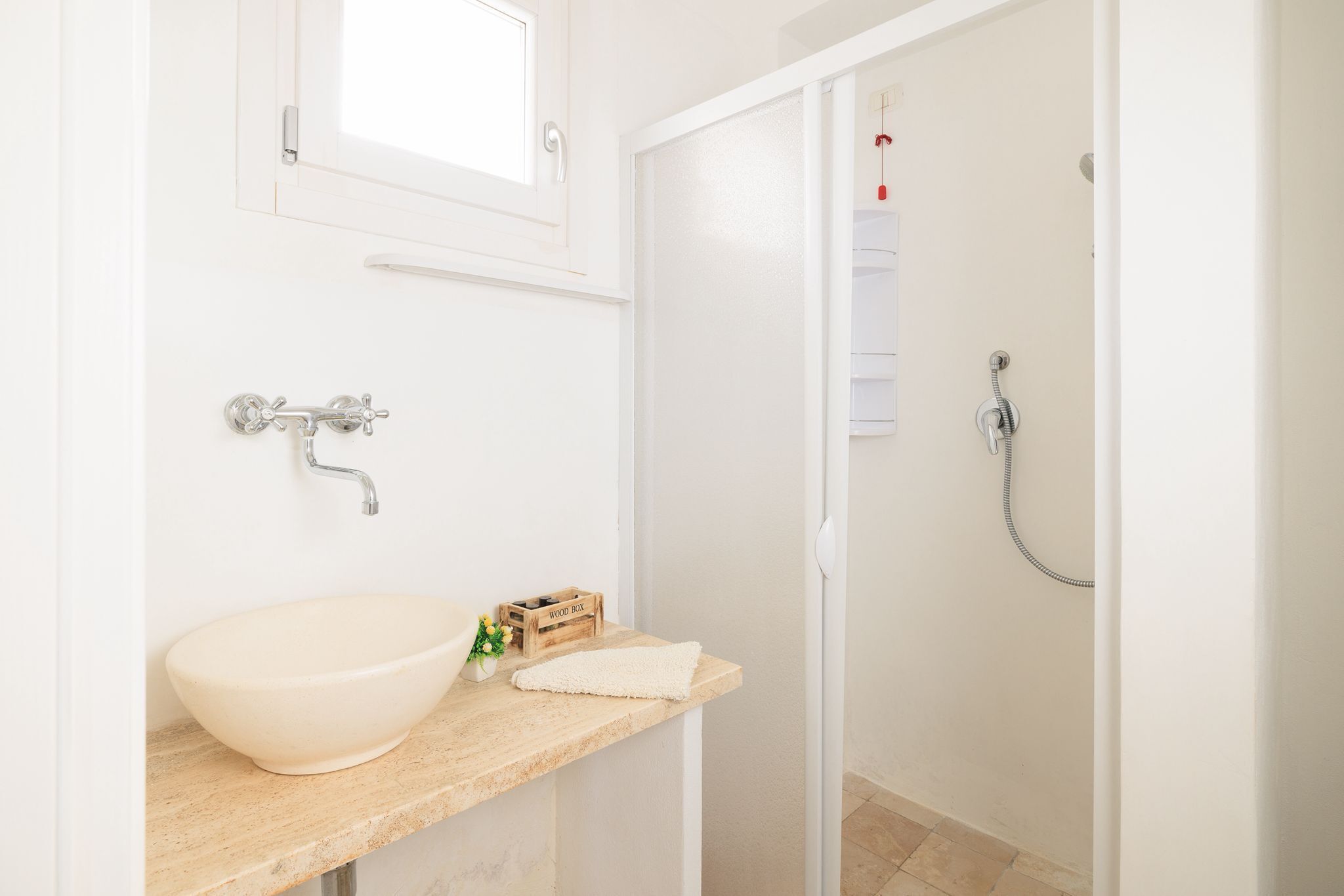 Un baño con un lavabo blanco, una caja de madera y una toalla sobre el mostrador.