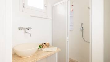 Un baño con un lavabo blanco, una caja de madera y una toalla sobre el mostrador.