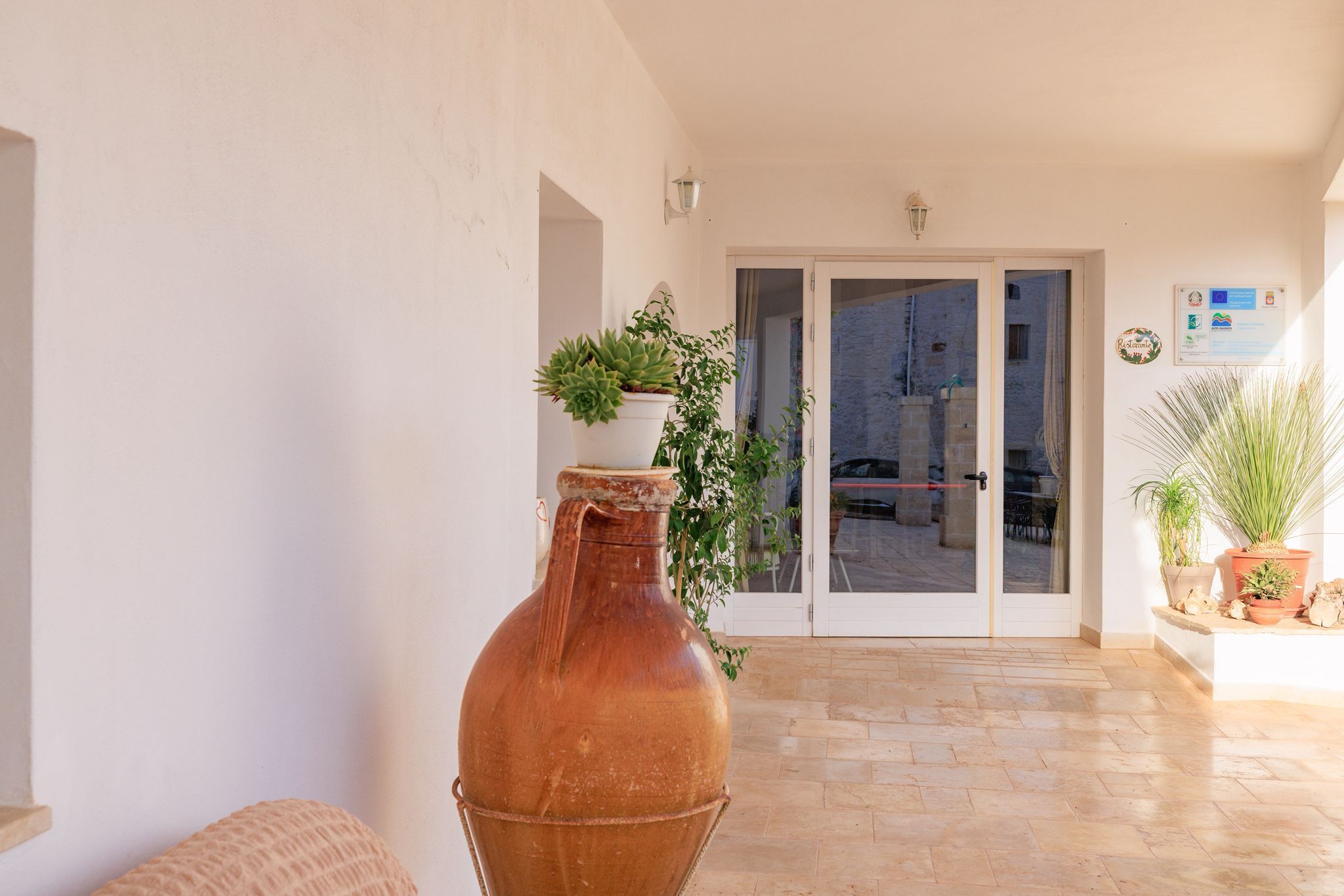 A spacious patio with a large terracotta pot, potted plants, and a sliding glass door leading to an outdoor area.