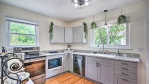 Cozinha moderna com armários brancos, eletrodomésticos de aço inoxidável e piso de madeira.
