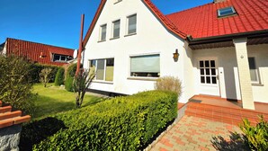 Ein zweigeschossiges Haus mit rotem Ziegeldach, weißen Außenwänden und einem kleinen Fenster.