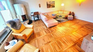 Ein gemütliches Wohnzimmer mit Steinwand, Kamin, einer Couch, einem Couchtisch und Holzboden.