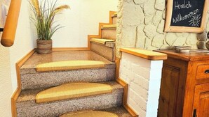 Eine Treppe mit einer Steinwand, einem Holzgeländer und einem Willkommensschild.