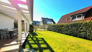 Eine Terrasse mit Sitzgelegenheiten im Freien, ein Kiesweg und ein gepflegter Rasen.