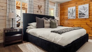 Ein Schlafzimmer mit einem großen Bett, Holzwänden und zwei gerahmten Bildern.