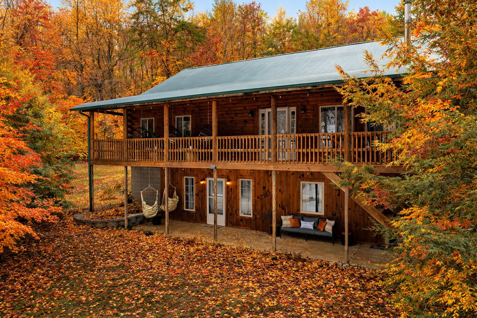 Une cabane dotée d’un balcon, d’une véranda avec des sièges et d’un espace couvert avec des fauteuils suspendus.