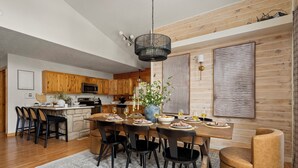 Eine moderne Küche mit Holzausbau, einer zentralen Kochinsel und einem Essbereich mit schwarzen Stühlen und einem runden Tisch.