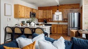 Eine moderne Küche mit Holzausstattung, Edelstahlgeräten und einem Essbereich mit Korbstühlen.