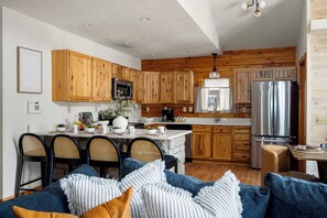 Una cucina moderna con mobili in legno, elettrodomestici in acciaio inox e un'area pranzo con sedie in vimini.