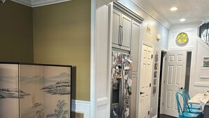 A dining area with a wooden table, chairs, a decorative screen, and a kitchen in the background. - Marvelous 3-bedroom townhome in vibrant upper Lawrenceville (Pittsburgh)