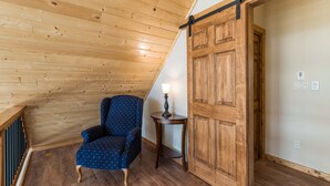 Una habitación con paneles de madera, una silla, una mesa y una puerta corredera.