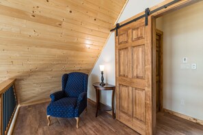A wooden-paneled room with a chair, a table, and a sliding door.