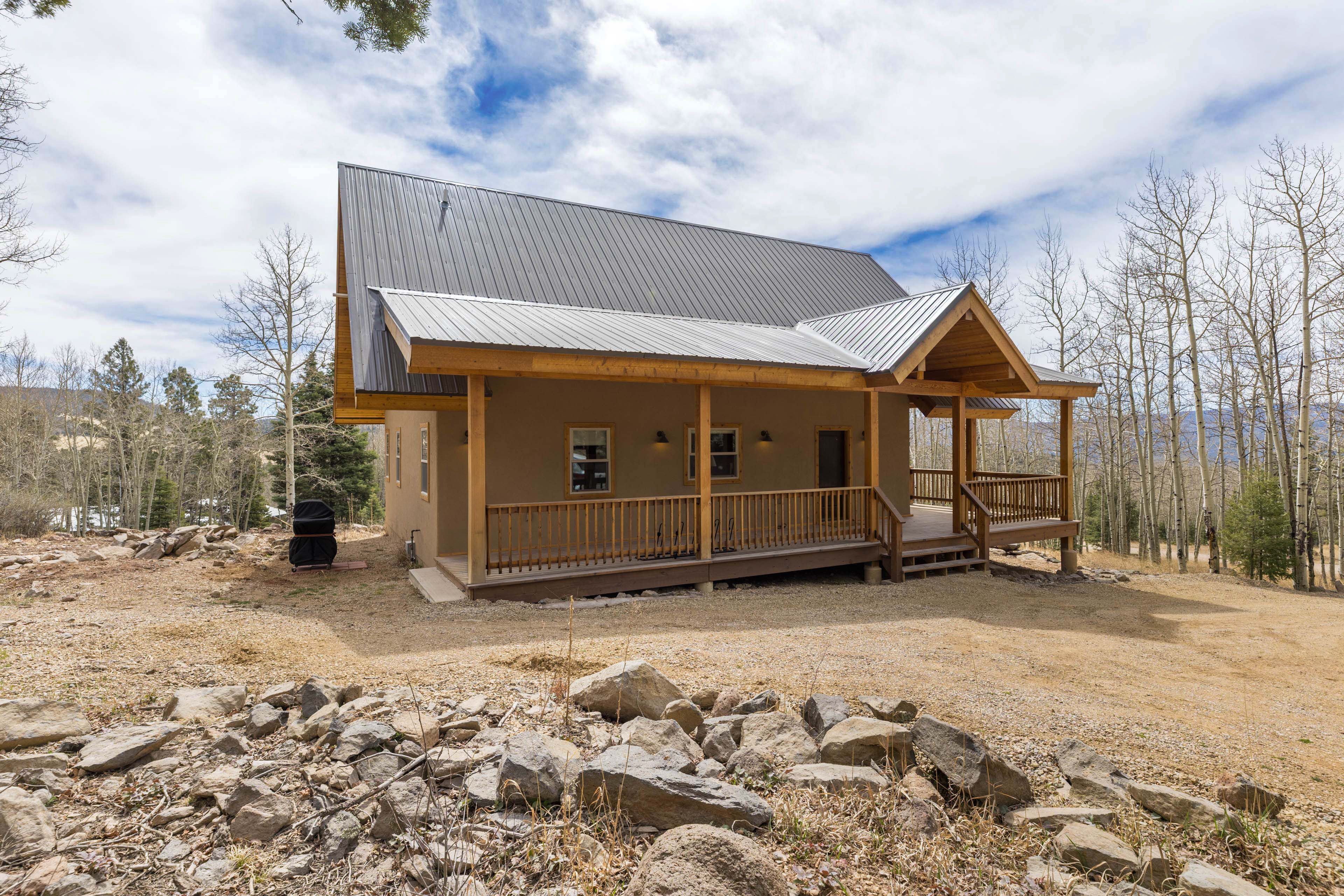 A cabin with a metal roof, wooden deck, and a gravel driveway.