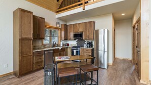Una cocina moderna con armarios de madera, electrodomésticos de acero inoxidable y un techo alto con vigas a la vista.