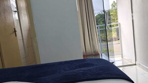 Un dormitorio con una cama, una puerta, un ventanal y vistas al exterior.