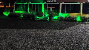 Un edificio de varios pisos con una cafetería en la planta baja, con amplias ventanas y fachada de piedra.