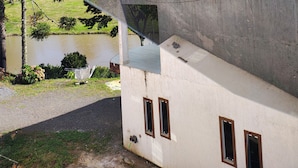 Un edificio de fachada de concreto, con una ventana visible y el reflejo del cielo y las nubes.