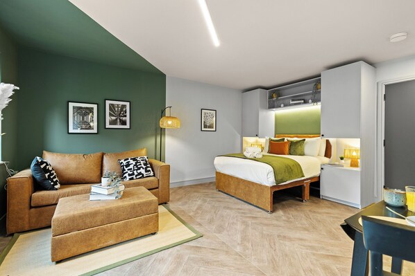 Ein modernes Hotelzimmer mit einer Couch, einem Bett, einem Schreibtisch und einem Essbereich.