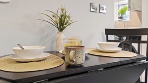 Eine Küchenarbeitsfläche mit einer weißen Schüssel, einer Keramiktasse und einer Vase mit Blumen.