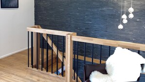 Ein modernes Interieur mit einer Holztreppe, einer dunklen Ziegelwand und einer hängenden Leuchte.