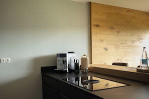 A modern kitchen with a built-in espresso machine, a knife block, and a wooden wall panel.