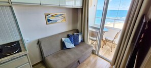 Una habitación con sofá, un cuadro, una zona de comedor con sillas y vistas al océano.