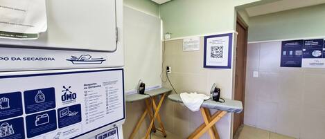 A hotel bathroom with a hand dryer, a towel rack, a mirror, and a QR code on the wall.