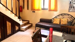 Una sala de estar con un sofá, una mesa de comedor y una escalera.