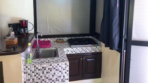 Una cocina compacta con un lavamanos, una estufa a gas y una pequeña zona de encimera.