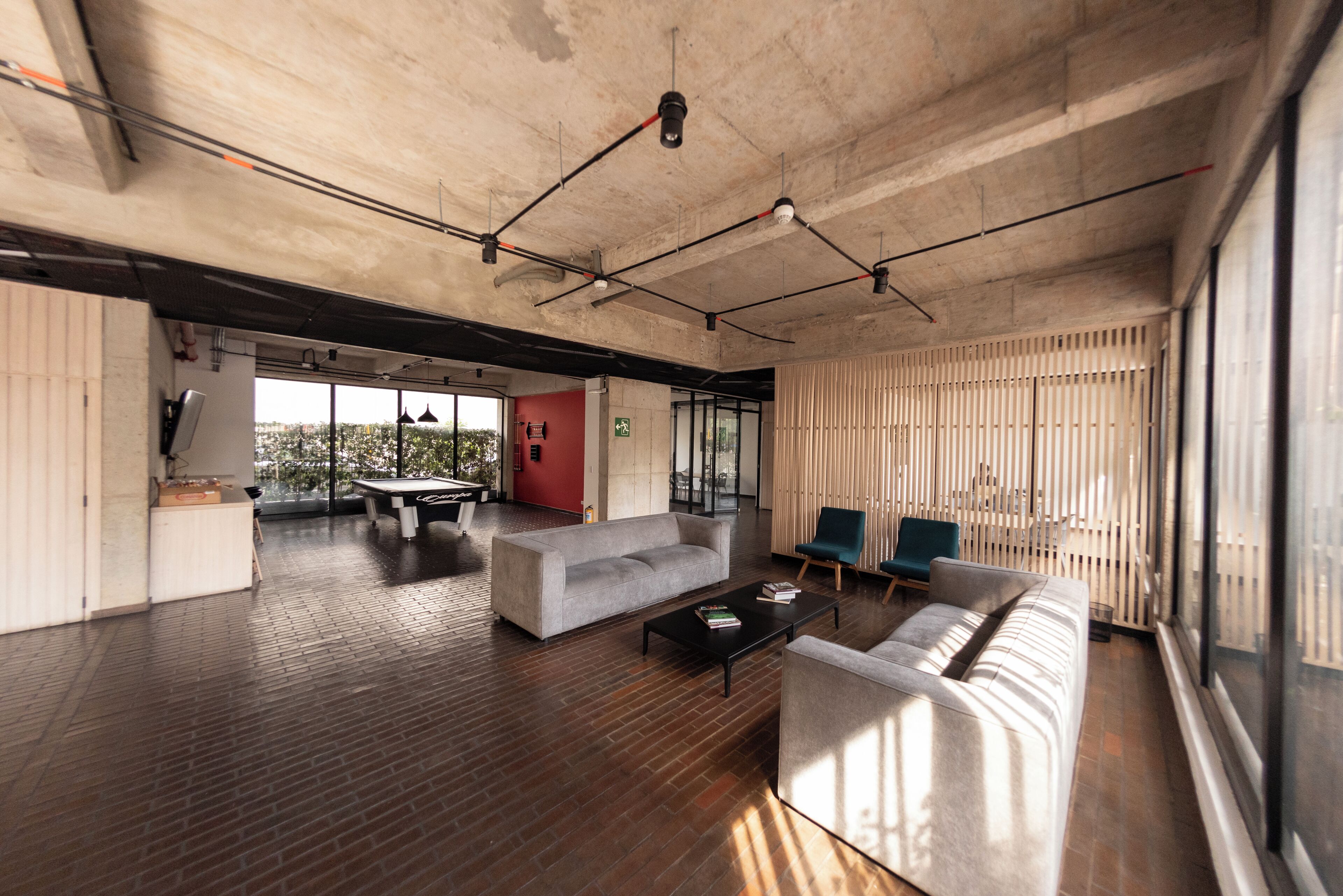 Un espace de vie à aire ouverte comprenant un canapé, une table basse et des fauteuils, une table à manger et une vue dégagée grâce à de grandes fenêtres.