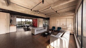 An open-plan living area with a sofa, coffee table, and chairs, a dining table, and a view through large windows. - Artistic Hub / Gourmet District Loft, Chapinero Alto (Bogotá)