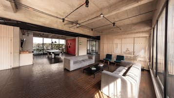 Un espace de vie à aire ouverte comprenant un canapé, une table basse et des fauteuils, une table à manger et une vue dégagée grâce à de grandes fenêtres.