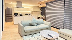 A modern living room with a sofa, a coffee table, and a kitchen in the background.