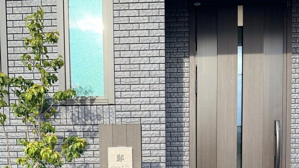 A modern building with a brick facade, a wooden door, and a mailbox.