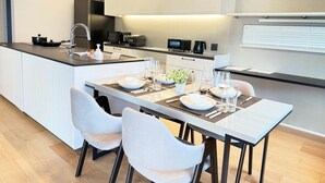 A modern kitchen with a dining area, white cabinetry, and a central island with a built-in stove.