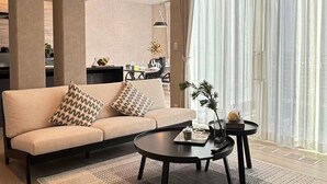 A modern living room with a sofa, coffee table, and a dining area in the background. - Akikawa Ozu 1 | 15 min to TSMC | Entire 3LDK House | Up to 6 Guests (Ozu)