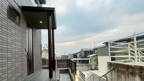 A modern building with a staircase leading to a covered outdoor area. - Akikawa Ozu 1 | 15 min to TSMC | Entire 3LDK House | Up to 6 Guests (Ozu)