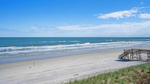 Ein Strand mit einer Holzkonstruktion, blauem Himmel und Meereswellen.