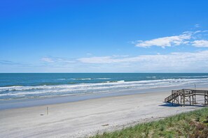 A beach with a wooden structure, clear sky, and ocean waves. - Summerhouse Oceanfront Condo + Pools/Pickleball/Tennis & More (St. Augustine)