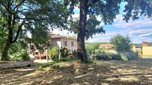 Uma casa rústica com parede de pedra, um pátio e vista para o campo.