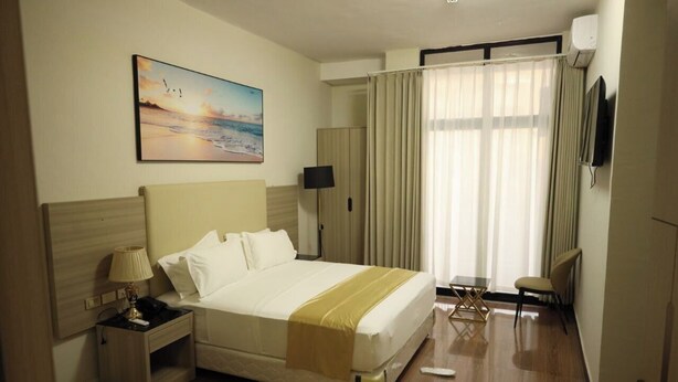 Una habitación de hotel con cama, mesita de noche, lámpara y un cuadro en la pared.