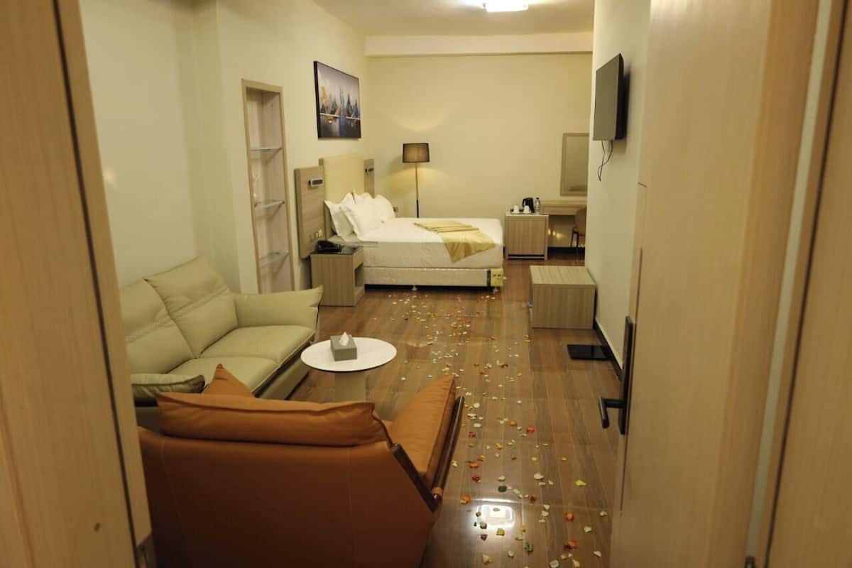 Ein Hotelzimmer mit einem Bett, einem Sofa, einem kleinen Tisch, einem Fernseher und einer Lampe.