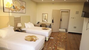 Habitación de hotel con dos camas, un escritorio, un espejo y una puerta.