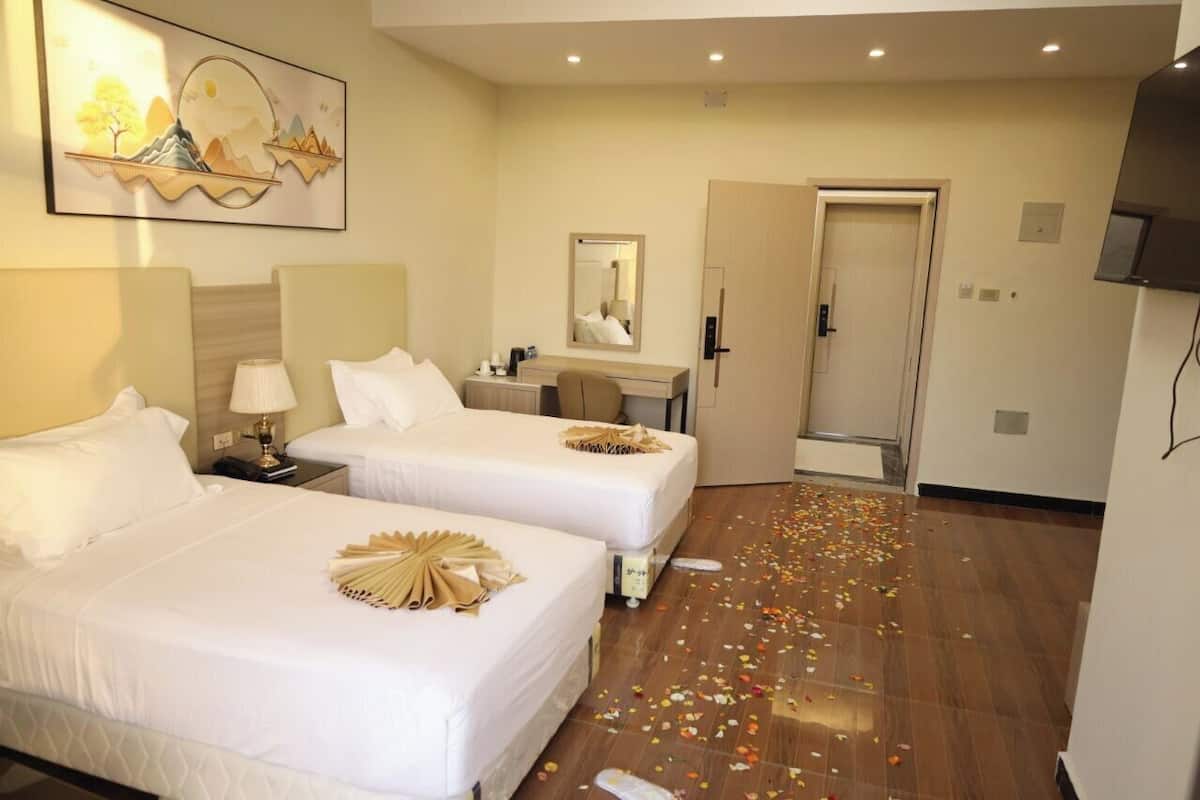 Ein Hotelzimmer mit zwei Betten, einem Schreibtisch, einem Spiegel und einer Tür.