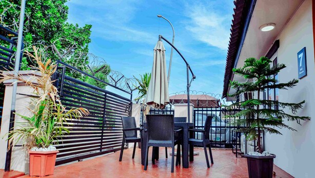 Eine Terrasse mit Tisch und Stühlen, Topfpflanzen und Blick auf die Straße.