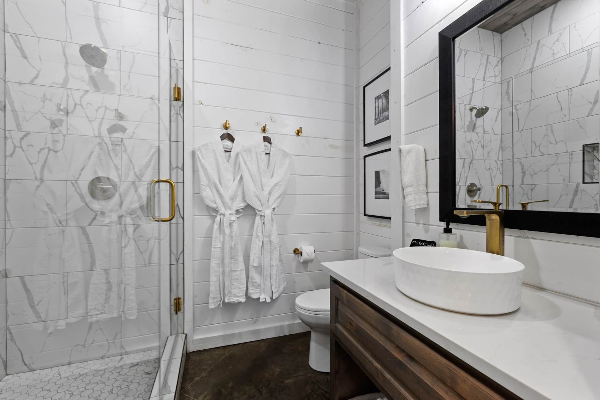 A modern bathroom with a marble wall, a round sink, and a large mirror.