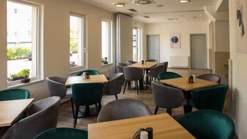Un comedor moderno con varias mesas y sillas, ventanas amplias y vistas al exterior.