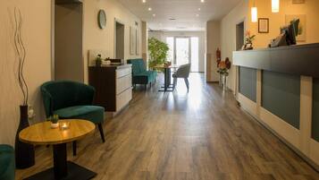 A hotel lobby with a reception desk, seating area, and a view of the outdoors.